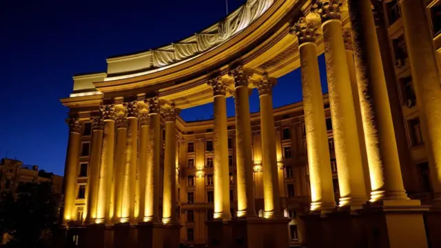 Будівля міністерства зовнішніх справ у Києві, освітлена золотим, ввечері на фоні синього неба