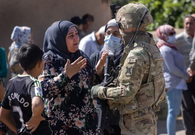 یک سرباز آمریکایی در حال صحبت کردن به یک زن سوری در یکی از روستاهای شمالی سوریه