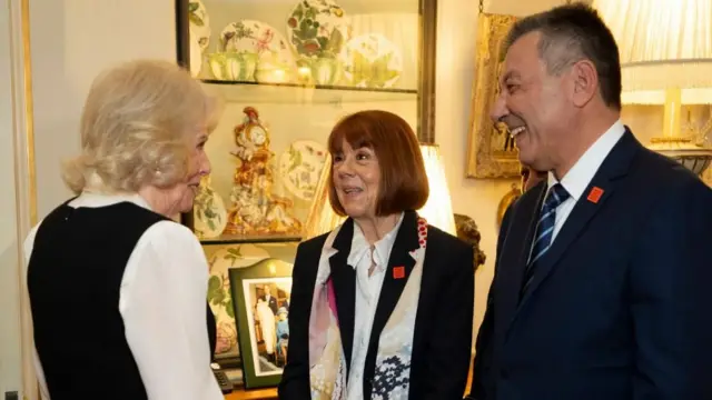 Kamila, Pelicot i Agopian rozmawiają w Clarence House, w tle widać ozdobną ceramikę.