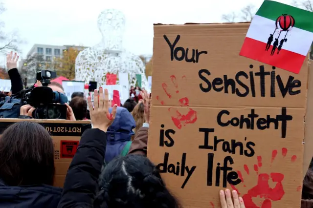 آذر ۱۴۰۱: یک مخالف حکومت ایران در تظاهراتی در فرانکفورت آلمان پلاکاردی را به دست دارد که روی آن خطاب به شبکه‌های اجتماعی نوشته «محتوای حساس برای شما، زندگی روزمره در ایران است.»