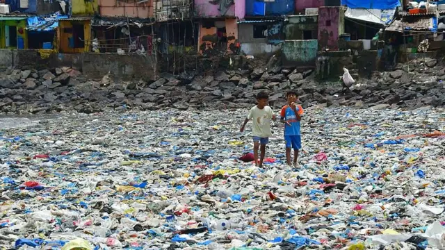 Niños caminando entre residuos plásticos