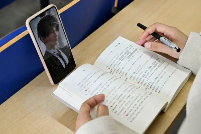 一本書前面擺著手機,手機上是一個遊戲角色