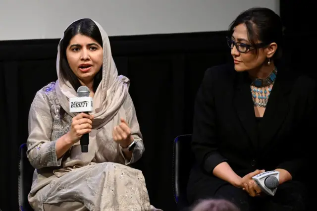 Malala falando com microfone na mão ao lado de Sahra