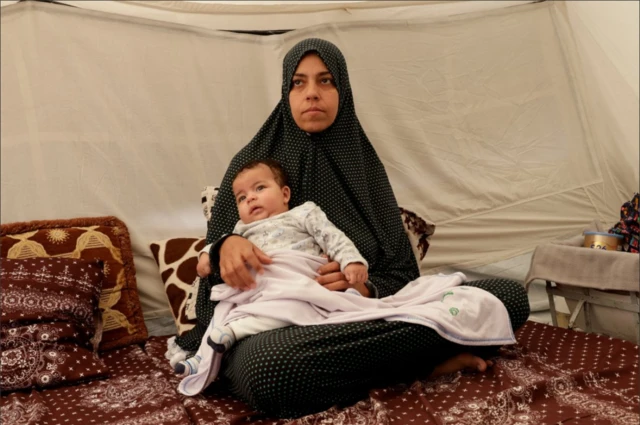 امرأة فلسطينية تجلس مع طفلها داخل خيمة في خان يونس جنوبي قطاع غزة، 1 مايو 2025.