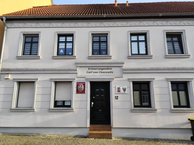 Uma casa branca com o nome de Clausewitz acima da porta
