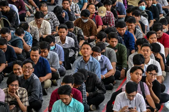 Para pencari kerja duduk di lantai sambil mengantre untuk memasuki bursa kerja yang diselenggarakan oleh pemerintah provinsi di Surabaya pada 24 September 2024.