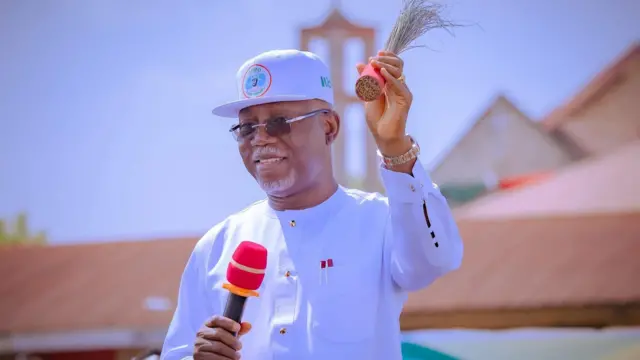 Aworan Gomina Lucky Aiyedatiwa pẹlu ẹrọ gbohungbohun lọwọ ọtun rẹ, igbalẹ idanimọ ẹgbẹ oṣelu APC lọwọ osi lasiko ipolongo ibo kan.