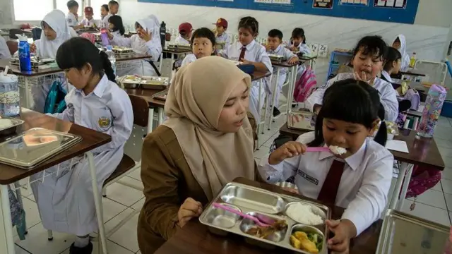 Guru memantau siswi menyantap makanan bergizi gratis di SD Angkasa 1, Bandung, Jawa Barat, Senin (6/1/2025).