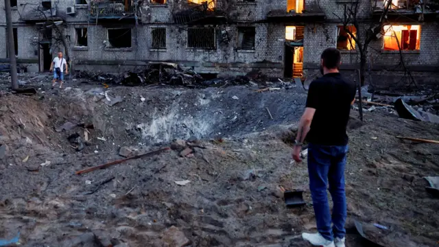 Dos hombres junto a un cráter cerca de un edificio en Kyiv.