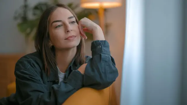 فتاة تنظر عبر نافذة وكأنها تفكر في شيء