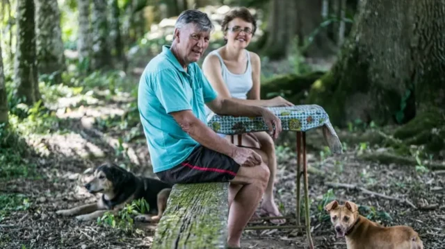 Homem e mulher sentadosfloresta com cachorro