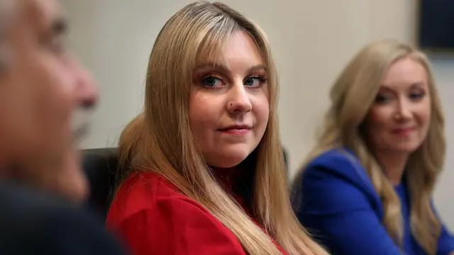 Abigail Zwerner, en el centro de rojo, mira a su derecha.