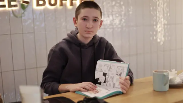 Сидящий за столом мальчик с книжкой