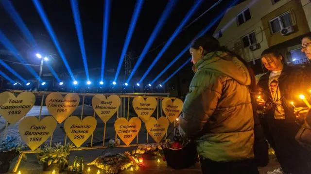 Девојчица окренута леђима камери гледа у бела срца именима жртава у Кочанима