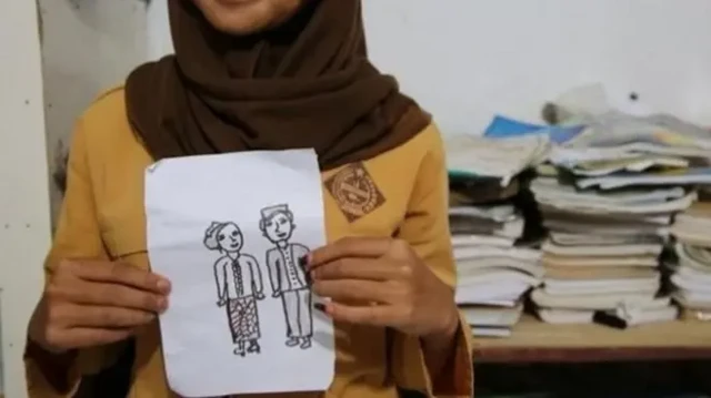 seorang perempuan memegang gambar sepasang pengantin