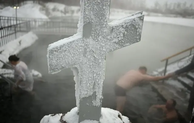 русија богојављање, богојављање у русији, Људи урањају у ледену воду језера у близини Ачаирског манастира током прославе православног хришц́анског празника Богојављања у Омској области, у Русији, ледени крст, залеђени православни крст