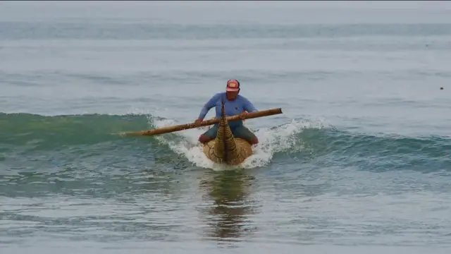 Homem pegando onda com canoa