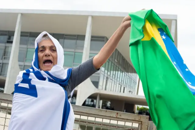 Manifestante enrolada na bandeiraprimeiro saque sportingbetIsrael segura uma bandeira do Brasilprimeiro saque sportingbetfrente ao prédio do STF