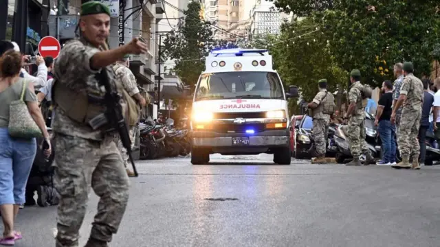 Ambulância seguindosaque minimo pixbetdireção a um hospital no Líbano, enquanto soldado observa.