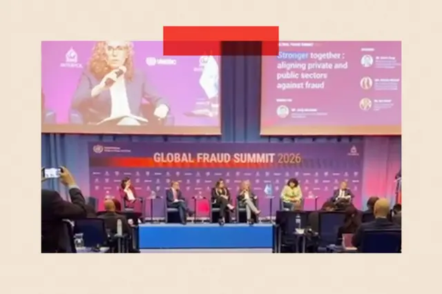 Một sân khấu với phông nền màu tím cùng dòng chữ 'Global Fraud Summit' phía sau, với sáu diễn giả đang ngồi trên sân khấu trước đông đảo khán giả