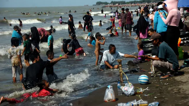 Wisatawan bermain air di pinggir Pantai Alam Indah, Tegal, Jawa Tengah, Minggu (23/04)