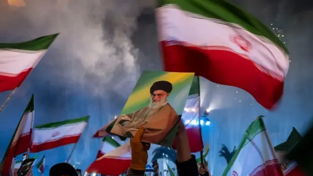 صورة خامنئي وأعلام إيران يرفعها متظاهرون موالون للنظام في البلاد