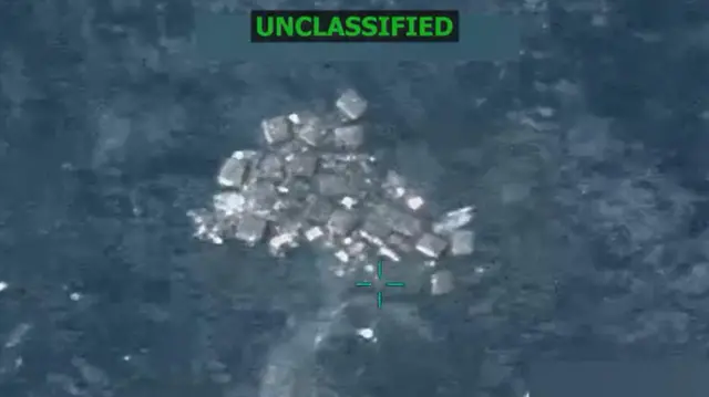 海に浮かんだ物体を上空から映した低精細の写真。上部には緑色で「UNCLASSIFIED」と示されている