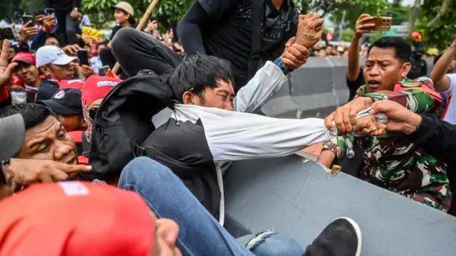Petugas mengamankan massa aksi di depan Kompleks Parlemen, Senayan, Jakarta, Kamis (28/8/2025).