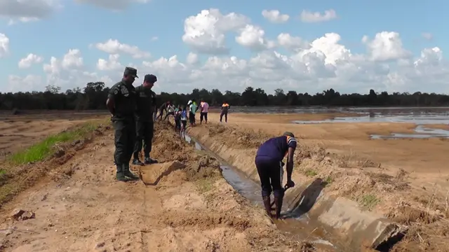 හානියට පත්ව ඇති ඇළ මාර්ගයක් පිළිසකර කරන පුද්ගලයින් පිරිසක්