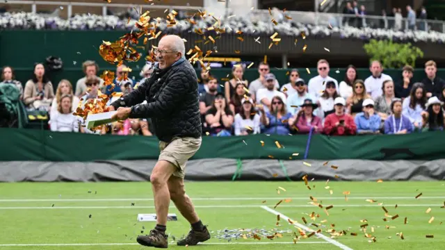 'जस्ट स्टॉप ऑईल' कार्यकर्ता टेनिस कोर्टवर कन्फेटी उडवताना.