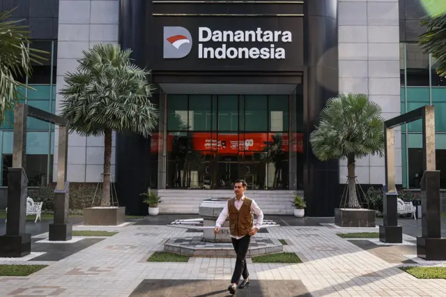 seorang pria melintas di depan gedung danantara.