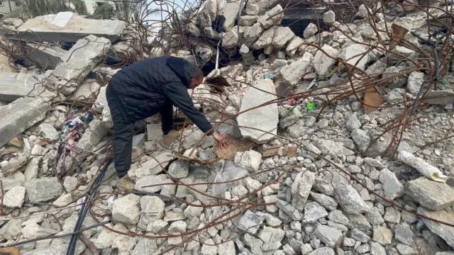 ढिगा-याखाली गाडल्या गेलेल्या व्यक्तीचा रहिवासी हाताने शोध घेत आहेत.