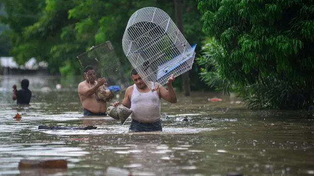 Hombre cargando una jaula, caminando por las calles inundadas de Poza Rica, en el estado de Veracruz