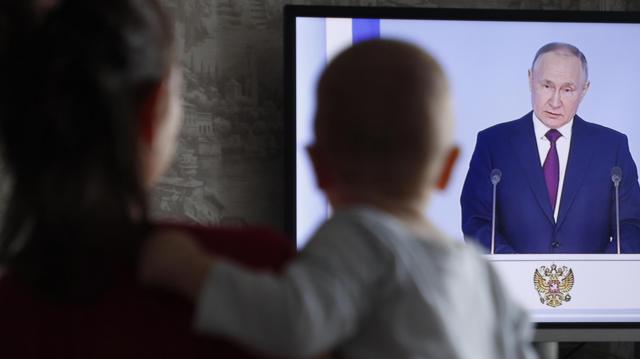 Russa assiste a discurso de Putin com criança de colo, em fevereiro de 2023