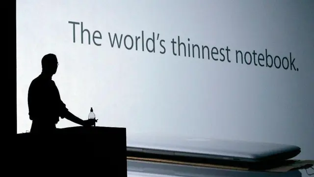 Силуэт человека на фоне большого белого экрана с надписью "Самая тонкая записная книжка в мире"