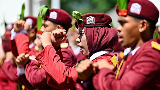Siswa memberi isyarat saat mereka menghadiri sebuah acara sebagai bagian dari program 'Sekolah Rakyat' (Sekolah Rakyat), sebuah inisiatif pemerintah yang menyediakan asrama, makanan, perawatan kesehatan, dan seragam untuk anak-anak kurang mampu di Darul Imarah di pinggiran Banda Aceh pada 8 Juni 2026
