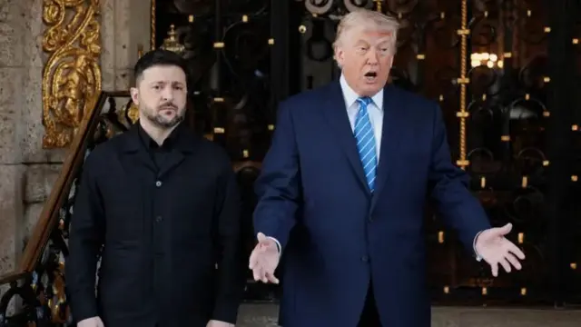 Ukraine President, Zelensky and US President, Donald Trump stand. Trump dey tok as e open im hands.