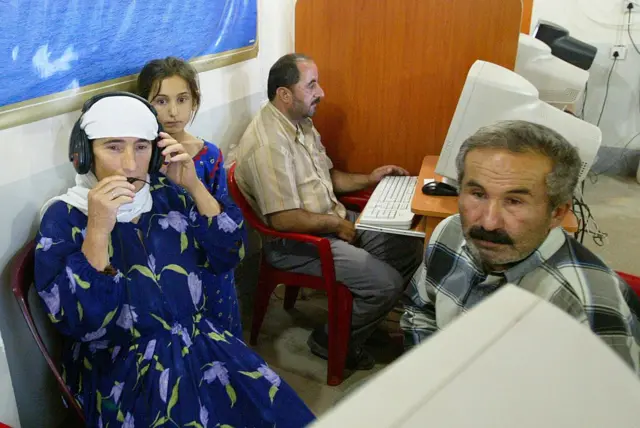 2005 yılına ait bu fotoğrafta kamp sakinleri, internet üzerinden uzakta yaşayan yakınlarıyla görüşmeye çalışırken görülüyor. Fotoğrafta bilgisayarlar başında iki adam, bir kadın ve bir küçük kız çocuğu görülüyor.