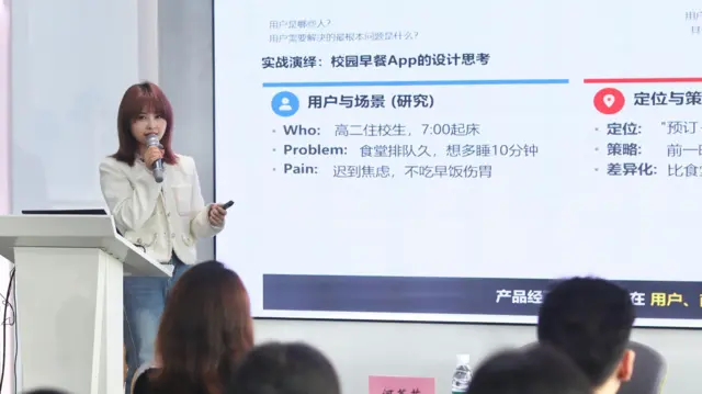 杨莎站在讲台上，右方是PPT