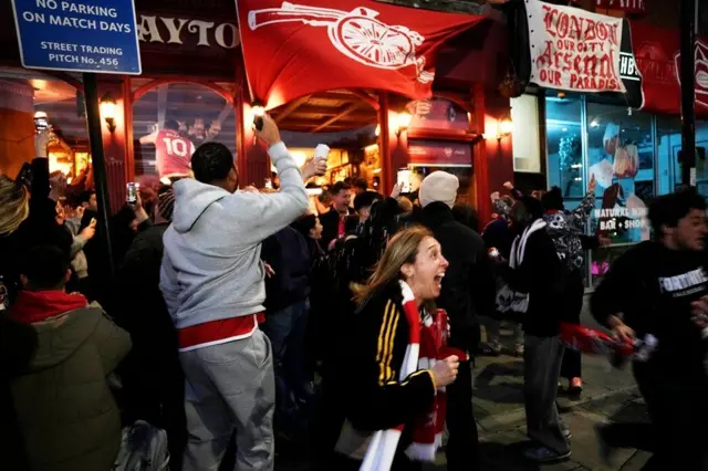 Navijači Arsenala okupili su se ispred stadiona kluba, Emirati, u severnom Londonu, čekajući ishod utakmice Mančester sitija i Bornmuta. Kada je sudija na toj utakmici odsvirao kraj, počelo je veliko slavlje 'tobdžija' uz vatromet