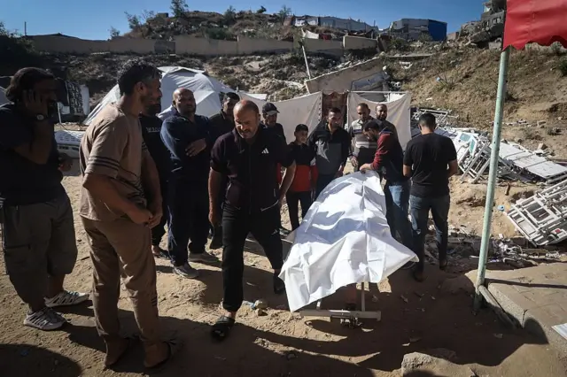 فلسيطينيون يحملون جثة شخص مغطاة بقماش أبيض.