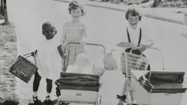 Uchegbu'yu yaklaşık 4 yaşındayken gösteren bir fotoğraf. Yanında iki kız çocuğu, önlerinde bebek arabalarıyla oynuyorlar.