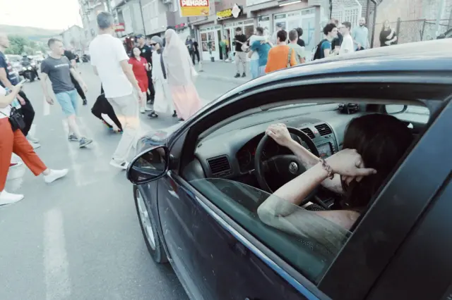 Muškarac u automobilu čeka da pređe ulicu