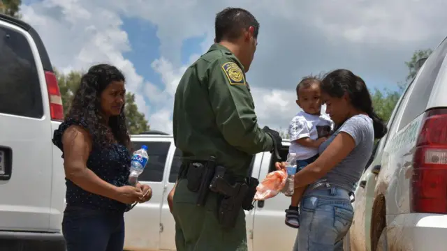 Dos jóvenes madres de Honduras, L y R, y sus respectivos hijos - un niño de 12 años, bloqueado, y un niño de 1 año - son detenidos por la Patrulla Fronteriza de Estados Unidos tras cruzar en balsa el río Bravo en la frontera entre EE.UU. y México el lunes 25 de junio de 2018, en Granjeno, Texas. (Foto de Jahi Chikwendiu/The Washington Post a través de Getty Images)