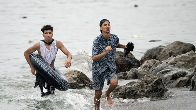 Dos migrasntes saliendo de la playa. 