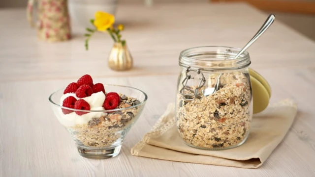 İki ayrı kasede granola ve müsli olduğu anlaşılan besinler görülüyor. Biri çilek ve yoğurtla süslenmiş
