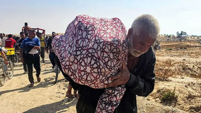 Пожилой человек несет мешок с продовольствием на плече