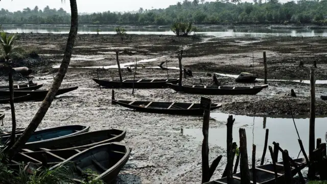 Les bateaux de pêche de l'Ogoniland sont maculés de boue huileuse au bord de la rivière
