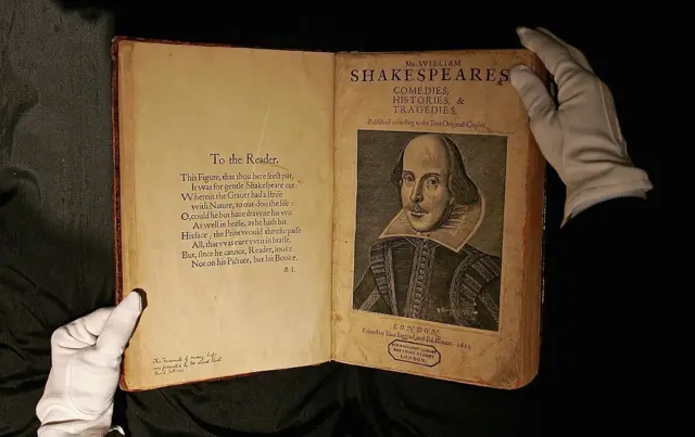 La première édition originale d'une œuvre de Shakespeare, ouverte entre les mains gantées d'un employé d'une maison de ventes aux enchères.
