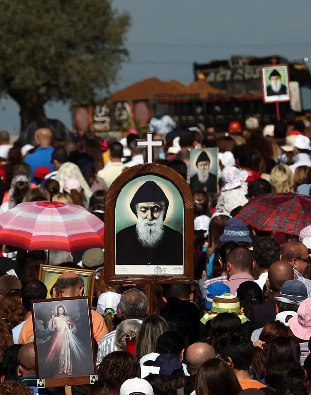 زوار يشاركون في مسيرة عند مزار القديس شربل في عنّايا شمال بيروت، حاملين صور المسيح وشربل، 22 أبريل 2016.